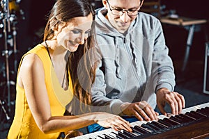 Piano teacher giving music lessons to his student