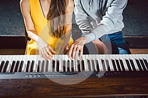 Piano teacher giving music lessons to his student