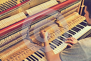 Piano tuning process. closeup of hand and tools of tuner working on grand piano. Detailed view of Upright Piano during a