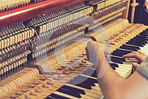 Piano tuning process. closeup of hand and tools of tuner working on grand piano. Detailed view of Upright Piano during a tuning.