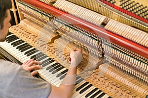 Piano tuning process. closeup of hand and tools of tuner working on grand piano. Detailed view of Upright Piano during a tuning