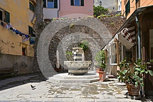 Piazza with a drinking water fountain from marble with lion heads in the old town of porto venere, Liguria, Italy