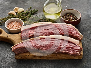 Picanha raw organic  beef steaks with seasoning over rustic dark background. Rump cap steak