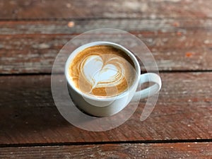 Piccolo coffee with heart latte art on rustic wood table