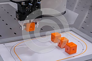 Pick and place robotic arm moving orange toy blocks at robot exhibition