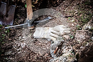 pickaxe and a spade in the garden, next to work gloves