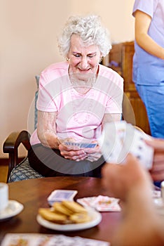 She picked up a good hand. seniors playing cards in their retirement home.
