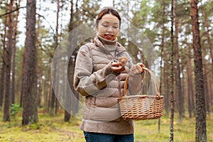 young woman picking mushrooms in autumn forest