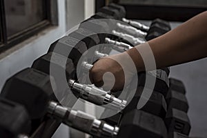 Picking up a 20 pounder from a rack of hex dumbbells at a gym or fitness club. Workout and pyramid training or running the rack