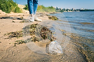 Picking up trash at the beach. Woman collect plastic bottles