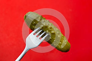 Pickle pricked on a fork on a red background