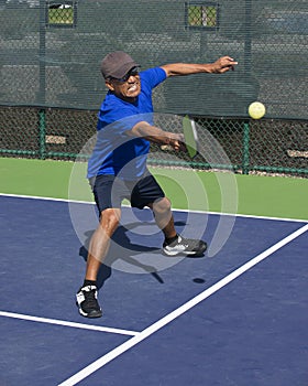 Pickleball Action - Man Wearing Blue Gritting Teeth While Stretching To Hit Forehand Shot