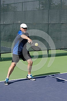 Pickleball Action - Senior Man Returning A Serve With A Backhand Stroke photo