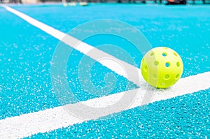 a pickleball ball on the line of a blue court, a new racket sport