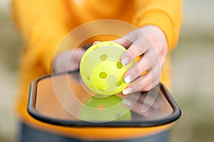 Pickleball paddle and yellow ball close up, woman playing pickleball game, hitting pickleball yellow ball with paddle