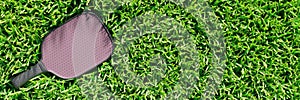 Pickleball racket on the lawn grass of a sports field.