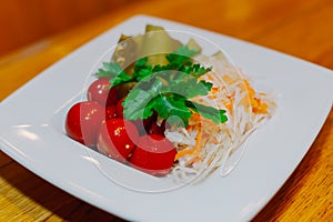 Pickled cabbage cucumbers tomatoes on one white plate with herbs on a wooden table. appetizer for vodka. close-up
