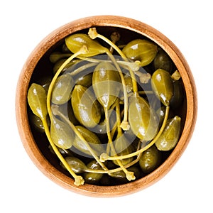 Pickled caper berries in wooden bowl over white