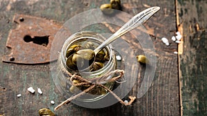 Pickled capers on a dark wooden background. Edible flower buds of Capparis spinosa, caper bush or Flinders rose. Delicious