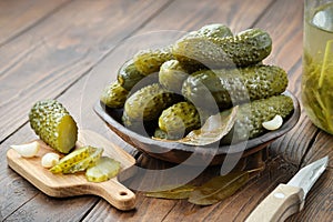 Pickled cucumbers in a bowl. Marinated cucumber slices on a cutting board. Homemade pickles