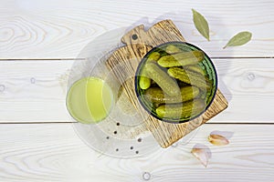 Pickled cucumbers in a ceramic bowl, pickle juice in glass. Homemade marinated gherkins. Top view.