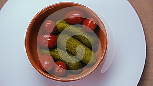 Pickled cucumbers and tomatoes in a clay plate.