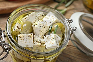 Pickled feta cheese in jar on wooden table