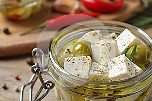 Pickled feta cheese in jar on wooden table