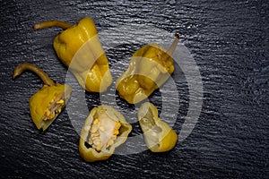 Pickled Golden Greek Peppers, Pepperoncini or Friggitelli sweet Italian chili pepper on natural stone background.