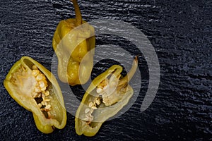 Pickled Golden Greek Peppers, Pepperoncini or Friggitelli sweet Italian chili pepper on natural stone background.