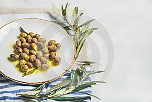 Pickled green Mediterranean olives and olive tree branch, copy space