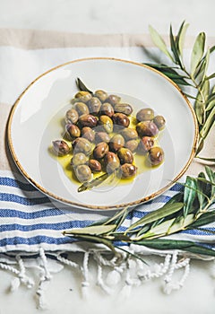 Pickled green Mediterranean olives and olive tree branch