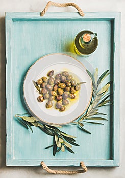 Pickled green Mediterranean olives, olive tree branch, virgin oil