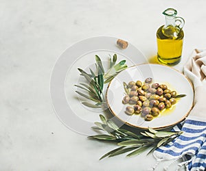 Pickled green Mediterranean olives, olive tree branch and virgin oil