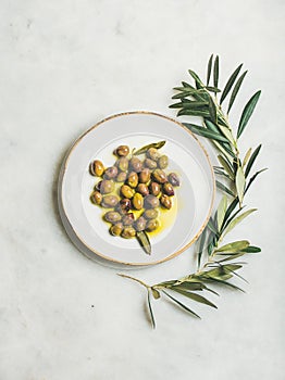 Pickled green Mediterranean olives in virgin olive oil on plate