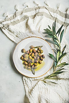 Pickled green olives in olive oil on white ceramic plate