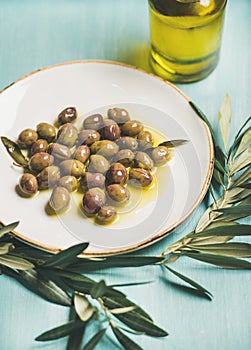 Pickled green olives, olive tree branch, virgin oil, selective focus