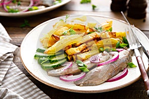 Pickled herring fillet with onion and fried potato on plate