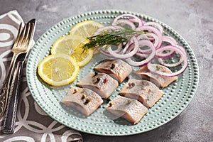 Pickled herring with red onion and lemon slices.