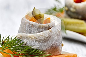 Pickled herring rolls with vegetables on wooden table