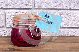 Pickled red cabbage in a clip glass storage jar with a label tag.