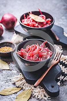 Pickled red onions in bowl on a gray background. Appetizer, condiment or topping, healthy fermented food photo