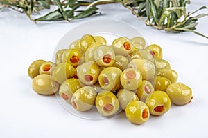 Pickled small green olives, filled with red sweet pepper in a wooden bowl. Fruits of Olea europaea, stuffed with bell pepper