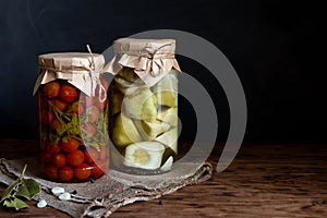 Pickled squash and tomatoes in a jar on a wooden table