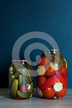 Pickled tomatoes and cucumbers in glass jars