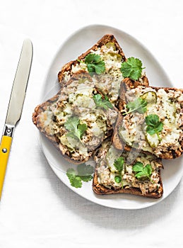 Pickles gherkins, canned tuna, cheese, multigrain bread baked sandwiches on a light background, top view. Delicious breakfast,