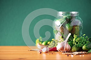 Pickling cucumbers in cans. Ingredients for marinated gherkins, glass jar, garlic, dill, salt, pepper on green