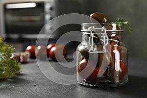 Pickling jar with fresh tomatoes on black kitchen table, closeup. Space for text