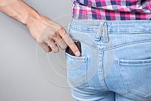 Pickpocketer`s hand pulling stealing wallet out of the back pocket, close up