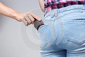 Pickpocketer`s hand pulling stealing wallet out of the back pocket, close up